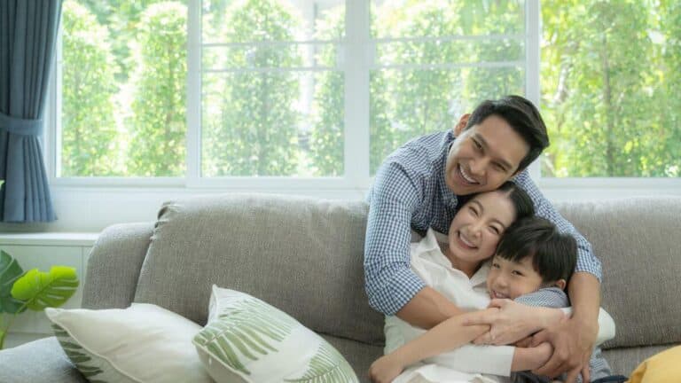 a happy family hugging each other on a sofa at home